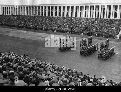 March of the honor guards of the Reich Labor Service with their flags and spades at the big parade of the RAD on the Zeppelin Field. In the background, the Zeppelin grandstand. Stock Photo