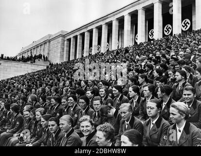 The female members of the Reich Labor Service watch their male colleagues from the grandstand during the big parade on the Zeppelin field. Stock Photo