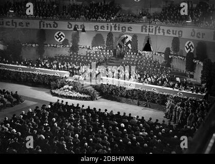'The Berlin Sportpalast is filled with people during the opening of the ''Week of the German Book''. Joseph Goebbels is giving a speech at this event. Behind him is an orchestra. Above him, the hall was decorated with swastika flags and the banner ''Books are the spiritual tools of the nation''.' Stock Photo