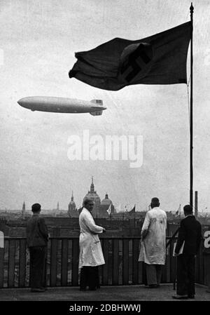 'The airship LZ 129 ''Hindenburg'' in the picture with a swastika flag over Berlin during an Olympic flight. In the background is an Olympic flag and the Berlin Cathedral.' Stock Photo