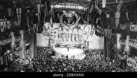 A gala ball of the French Navy at the Paris Grand Opera in February 1939. Guests await the opening speech against the backdrop of a stylized battleship turret. Stock Photo