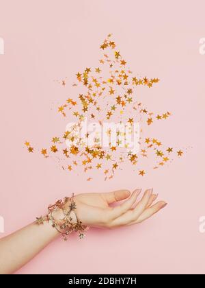 Christmas tree made from golden confetty stars on pink background. Minimal Christmas card Stock Photo