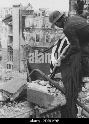 A German soldier lays out a swastika flag as identifying mark for airplanes. Stock Photo