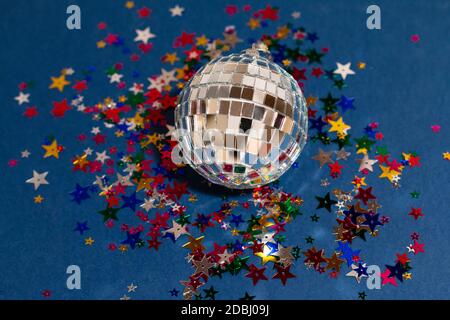 silver disco ball with colored sparkles on blue background, greeting card wallpaper template with empty space for text Stock Photo