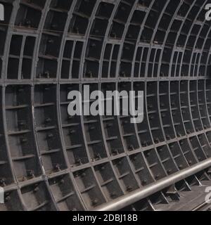 Dark dusty surface of deep-running underground tunnel with bolted joints of prefabricated reinforced lining for texture or abstract background. Stock Photo