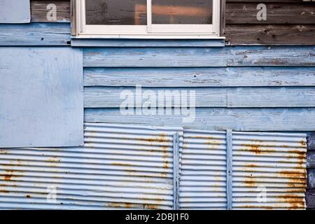 Wooden wall of an old house patched up with corrugated metal panels, painted light blue; Sadamisaki Peninsula, Japan Stock Photo