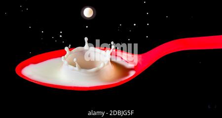 White milk splashing into red spoon Stock Photo