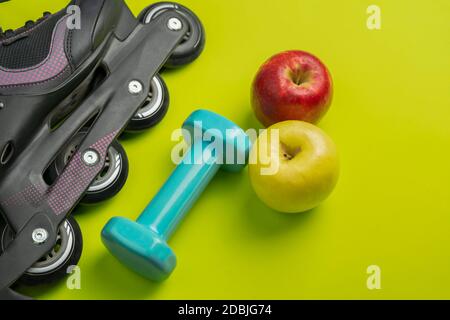 Sport fitness equipment flat lay with healthy food .Two apples ,dumbbell,roller skate, and headphones on green background .Top view healthy lifestyle Stock Photo