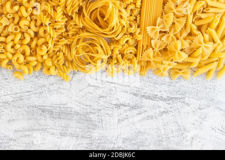 Italian foods concept and menu design. Various kind of Pasta Farfalle, Pasta A Riso, Orecchiette Pugliesi, Gnocco Sardo and Farfalle on white stone background with flat lay. Copy cpase Stock Photo