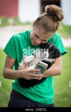A teen age girl takes a selfie with a puppy on a farm in St Anne, Wisconsin. Stock Photo