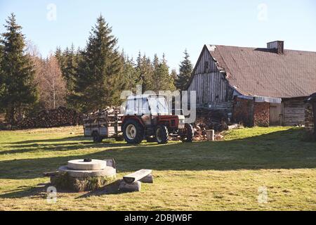 Old tractor with firewood by buildings in remote village in Jizera Mountains, Poland. Stock Photo