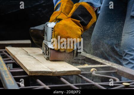 Wood sanding process by using handheld electric belt sander Stock Photo