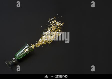 A spilled glass with golden glitter on black background Stock Photo