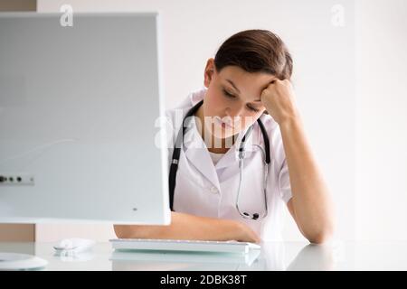 Frustrated Overworked Sad Doctor At Computer In Hospital Stock Photo ...