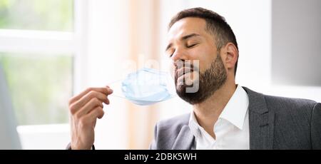 Man Removing Face Mask To Breath Freely Stock Photo