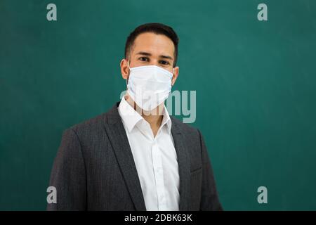 School Teacher Standing In Class Wearing Face Mask Stock Photo
