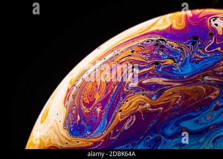 Abstract background made from soap bubble reflecting light. Rainbow soap bubble on a dark background. Stock Photo