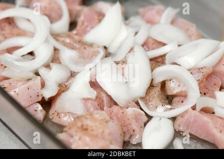 Sliced poultry meat with onions, lying on a baking sheet and ready to bake Stock Photo