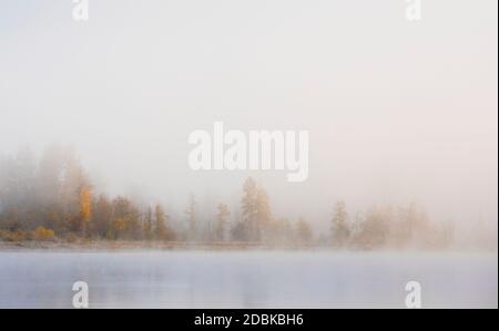 Fog rises off of One Mile Lake on a crisp fall morning in Pemberton, British Columbia. Stock Photo