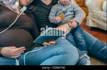 Family with child and pregnant mother looking tablet Stock Photo