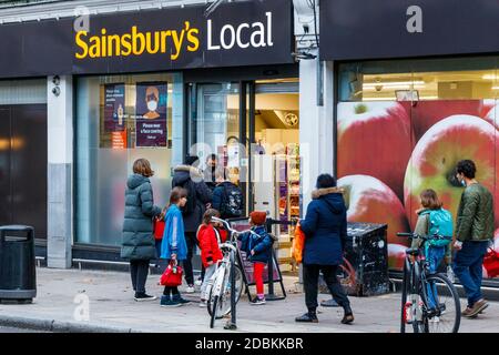 Customers queuing at Sainsbury's Local in Fortess Road, open for essentials during the second coronavirus pandemic lockdown, Tufnell Park, London, UK Stock Photo