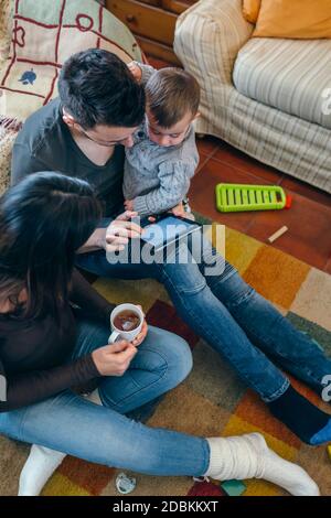 Family with child and pregnant mother looking tablet Stock Photo