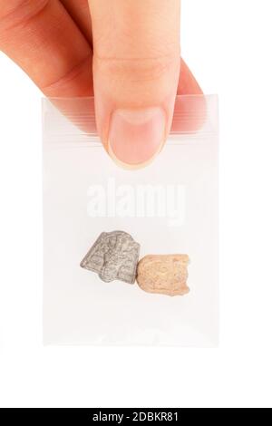 Ecstasy pills in plastic bag in dealers hand isolated over white. Stock Photo