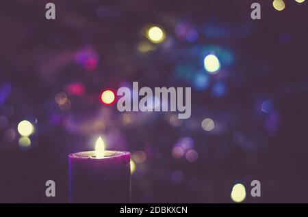 one burning candle concept with shining bokeh glittering ligts on christmas tree on background Stock Photo
