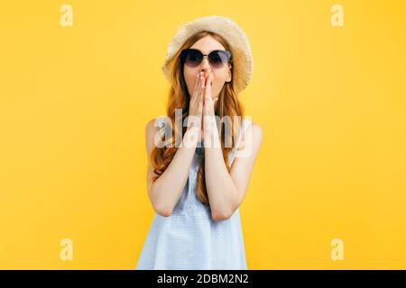 Shocked surprised girl in sunglasses and a summer hat, on a yellow background. Travel, vacation, summer Stock Photo