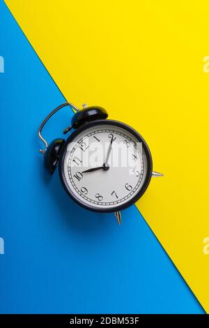 Alarm clock on a blue and yellow background. Business Concept Stock Photo