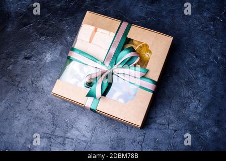 Box with satin ribbons and delicious treats for New Year and Christmas. New Year's desserts on a dark background. New Year's content