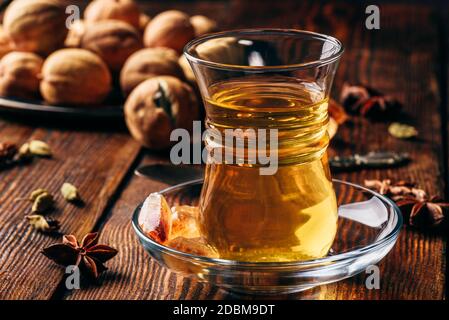 Arabic tea with star anise, cardamom and dried lime in oriental glass over wooden surface Stock Photo