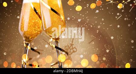 Two glasses of champagne toasting and golden lights against gold background Stock Photo