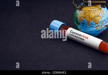 CORONAVIRUS LOCKDOWN text with world globe, key and Blood test vacuum tube on black background. Covid-19 or Coronavirus Concept Stock Photo