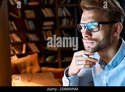 Close up view of focused businessman wear computer glasses looking at pc screen. Stock Photo