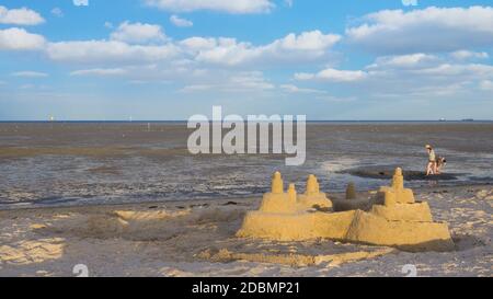 Sandburg am Strand vor Wattenmeer an der Nordsee mit Wolken am blauen Himmel Stock Photo