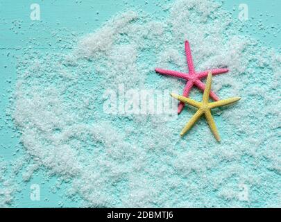 Two beautiful colored starfish lie on artificial sea foam on turquoise wooden background. Sea vacation concept. Place for text. Banner template. Stock Photo