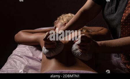 Massage with bags on a black background , the girl lies in the dark, blonde, face closed Stock Photo