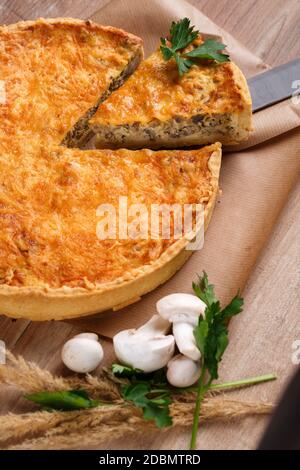 Traditional vegetable pie on rustic wooden table. Sliced slice of pie stuffed with mushrooms and cheese. Close up. Selective focus. Stock Photo