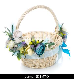 Easter basket on white background. Decorated with flowers in blue and a small decorative sheep. Ribbons and lace. Close up. Stock Photo
