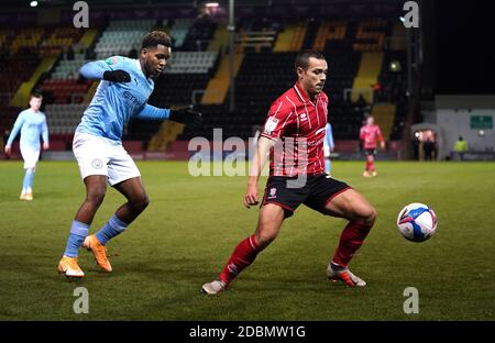 Lincoln City’s Remy Howarth and Manchester City's Jayden Braaf (left) battle for the ball during the Papa John's Trophy match at Sincil Bank, Lincoln. Stock Photo