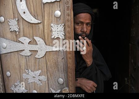 Man pictured at the Sidi Yahia Mosque next to old wooden door in Timbuktu, Mali, West Africa Stock Photo