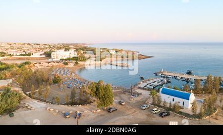 Aerial view of coastline sunset and landmark white washed chapel at Agia Triada beach, Protaras, Famagusta, Cyprus from above. Bird's eye view of tour Stock Photo