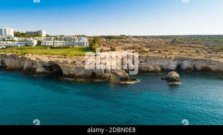 Aerial view of coastline and landmark Love bridge, international sculpture park and sea caves, at Cavo Greco, Ayia Napa, Famagusta, Cyprus from above. Stock Photo