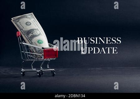 Shopping cart with words BUSINESS UPDATE on dark background. Business, Copy space and online shopping concept. Selective focus Stock Photo