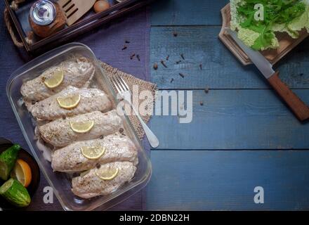 Marinated Turkey wings in a tray on a wooden table, prepared for roasting in the oven. There are spices and herbs nearby. Top view, copy space. Stock Photo