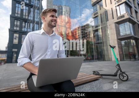 Young man in white shirt working on a laptop outdoors Stock Photo