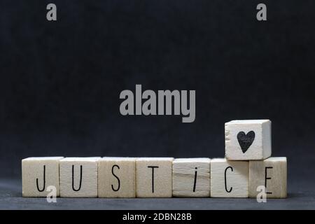 Wooden cubes with the word Justice on black background, Black lives matter concept with hearts symbol dark Stock Photo