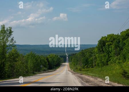 A straight long asphalt road running through the mountain divided the mountain into two parts Stock Photo