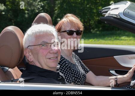 Happy older couple drives with a luxury convertible car on a sunny day Stock Photo